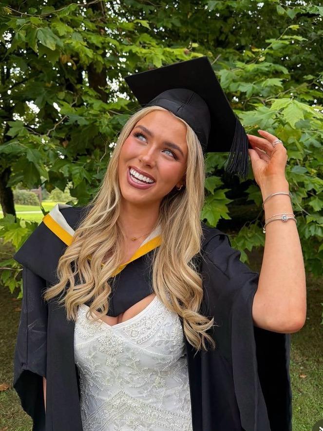 Aideen laughing outdoors in her graduation cap and gown